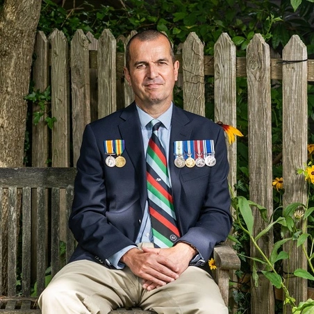 Charlie sat on bench wearing medals_square Charlie on bench wearing medals