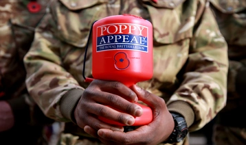 Royal British Legion Poppy Appeal collector in battledress holding red collection box
