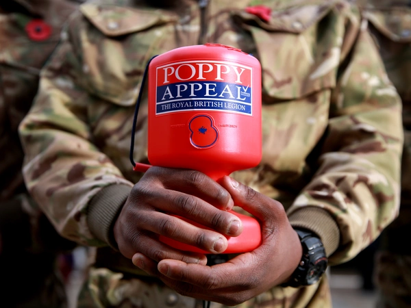 Royal British Legion Poppy Appeal collector in battledress holding red collection box