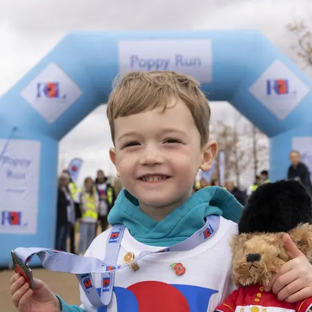 Young boy with his medal and teddy at the Poppy Run finish line