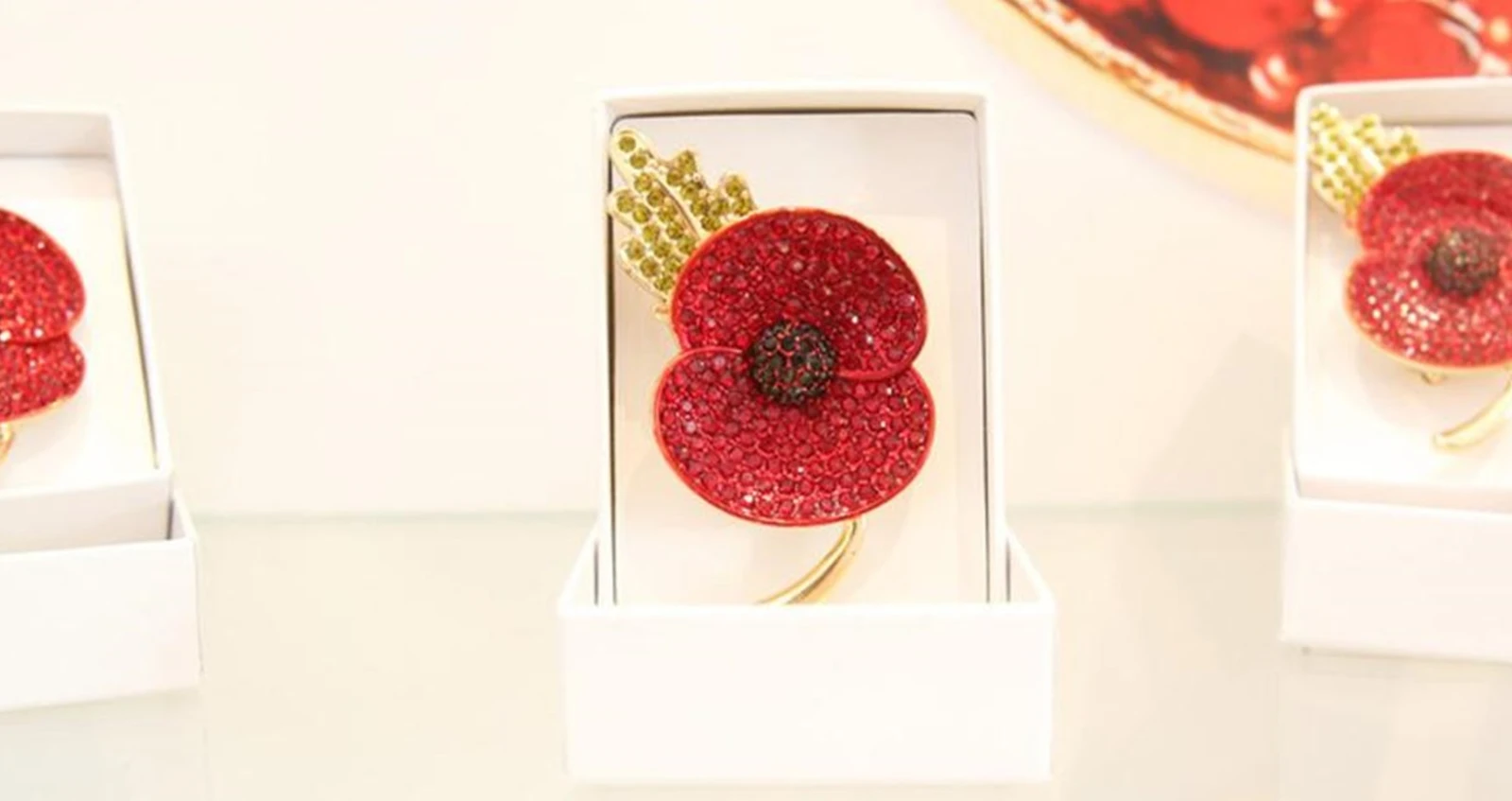 Three jewelled poppy lapel pins in boxes