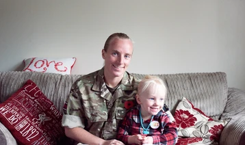 Army Healthcare Assistant in battledress at home with young daughter