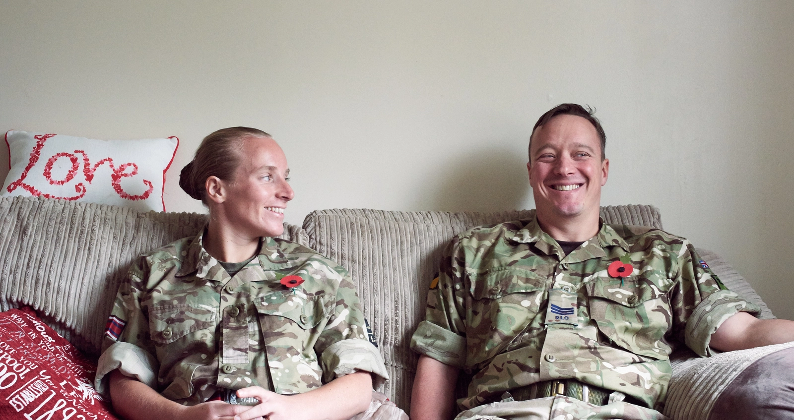 Military couple, and members of the Legion, sitting on sofa at home in battledress 