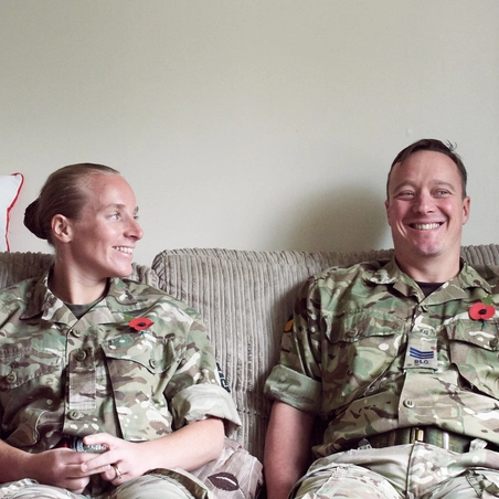Military members couple Military couple, and members of the Legion, sitting on sofa at home in battledress