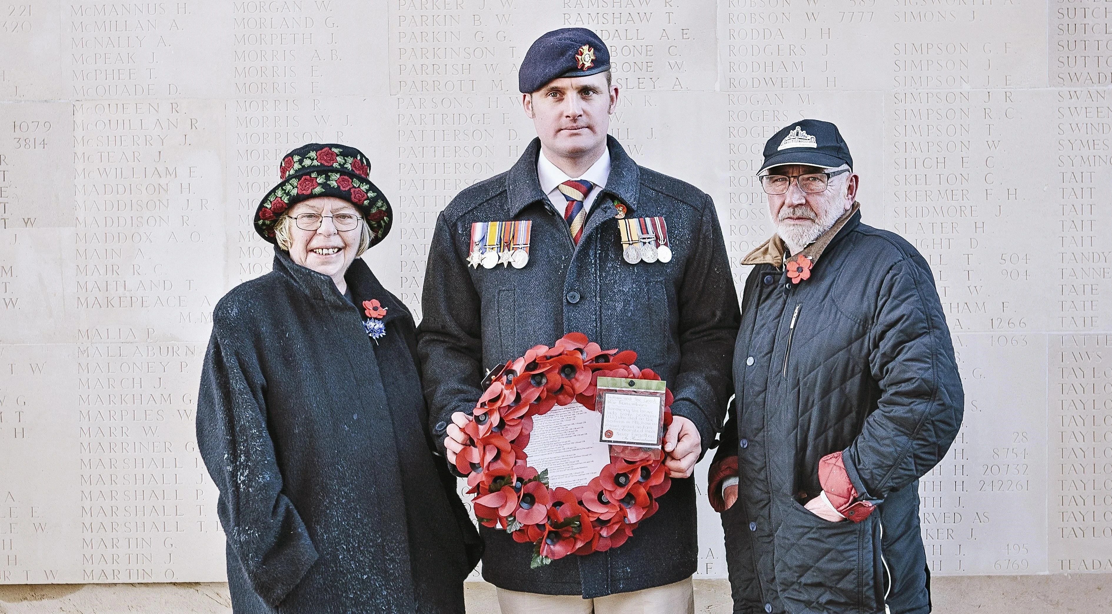 Liam Young poses with his fellow members and holds a poppy wreath