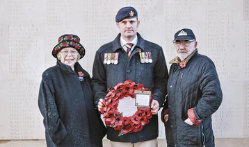 Liam Young poses with his fellow members and holds a poppy wreath