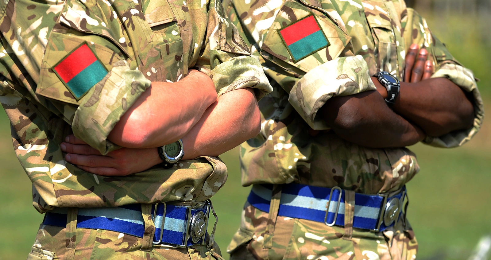 Two soldiers in camouflage uniform with crossed arms