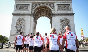 Pedal to Paris 2018 cyclists sporting the Legion's t-shirts, walking towards L'Arc de Triomphe in Paris at the end of the ride.