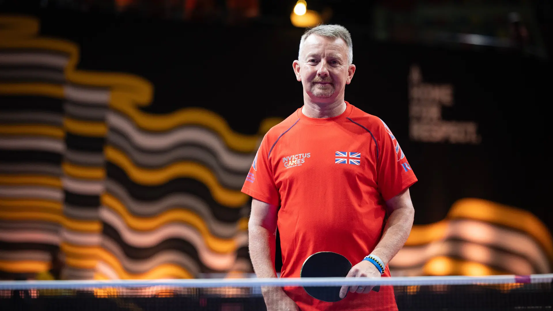 Al Dyer stood holding a bat at a table tennis table at the Invictus Games in Germany