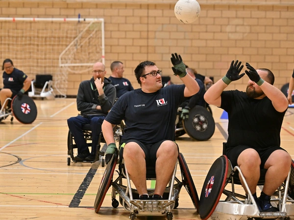Matthew Trigg playing wheelchair rugby, reaching for the ball in the air
