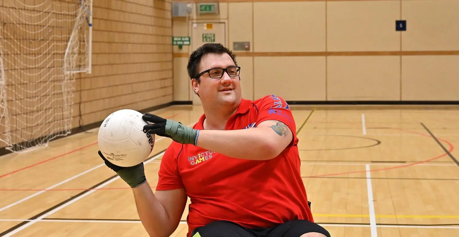 Matthew Trigg playing wheelchair rugby, wearing a red Team UK t-shirt
