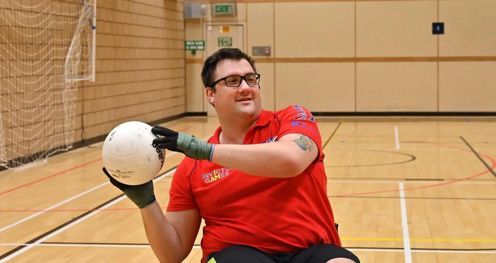 Matthew Trigg playing wheelchair rugby, wearing a red Team UK t-shirt