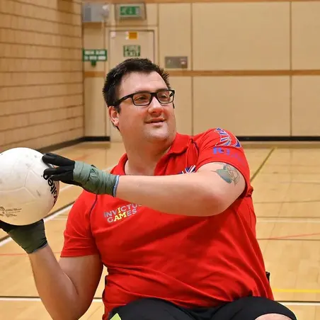 Matthew Trigg playing wheelchair rugby, wearing a red Team UK t-shirt