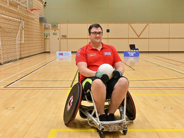 Matthew Trigg sat in a wheelchair holding a ball Matthew Trigg sat in a wheelchair holding a ball