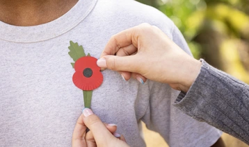 A new plastic-free poppy being pinned onto the left side of a persons chest