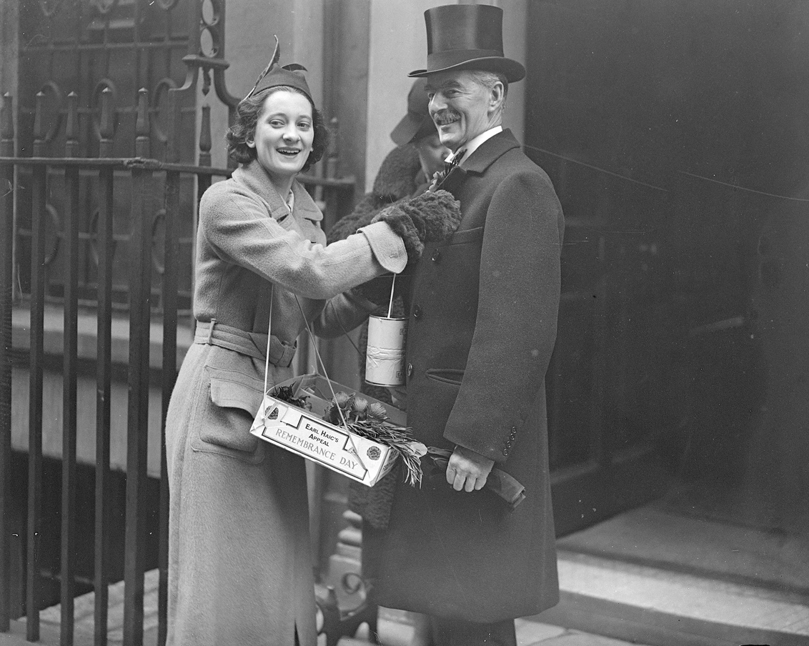 Neville Chamberlain receiving a poppy from a volunteer in 1937
