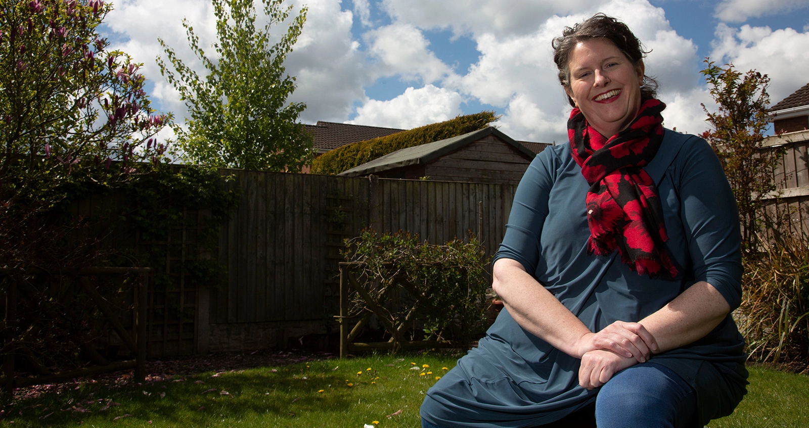 Woman sat outside on bench smiling