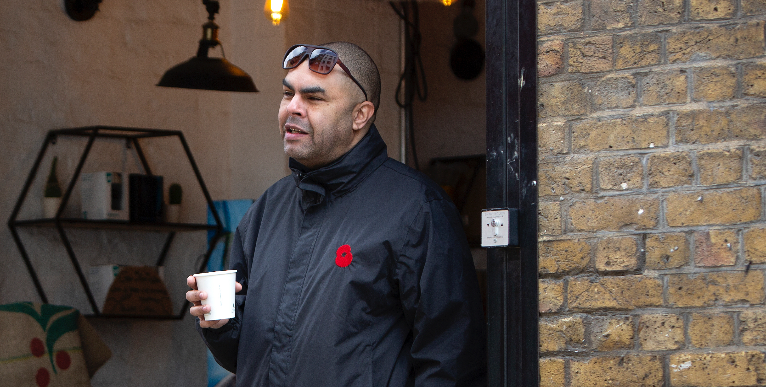 Man leaning on door with cup of tea