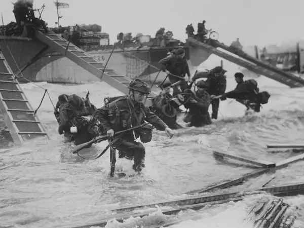 Black and white image showing Soldiers leaving their boats to fight on D-Day