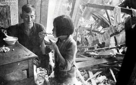 Chinese civilains sitting amid ruins of a building