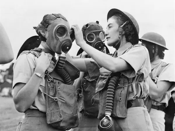 A South African Women's Auxiliary Air Force Sergeant Instructor fitting a gas mask to a beginner