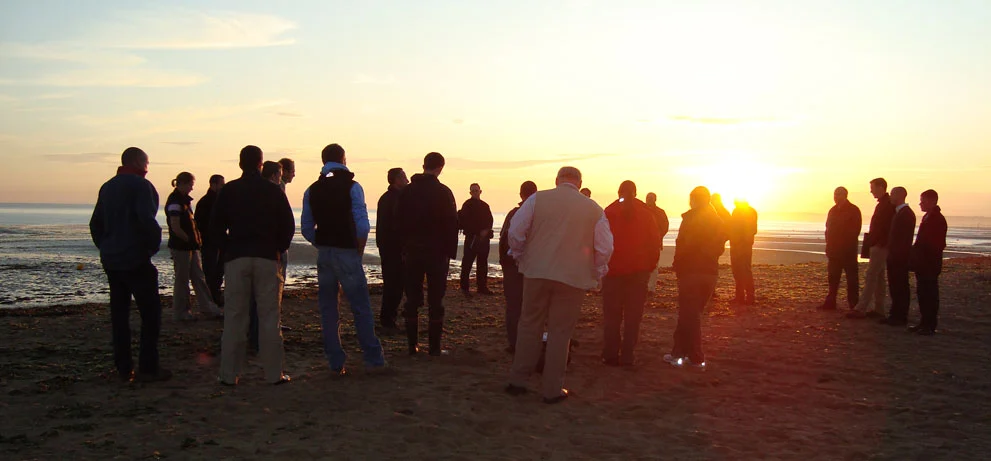 People gathered at sunset on a Normandy beach remembering D-Day.