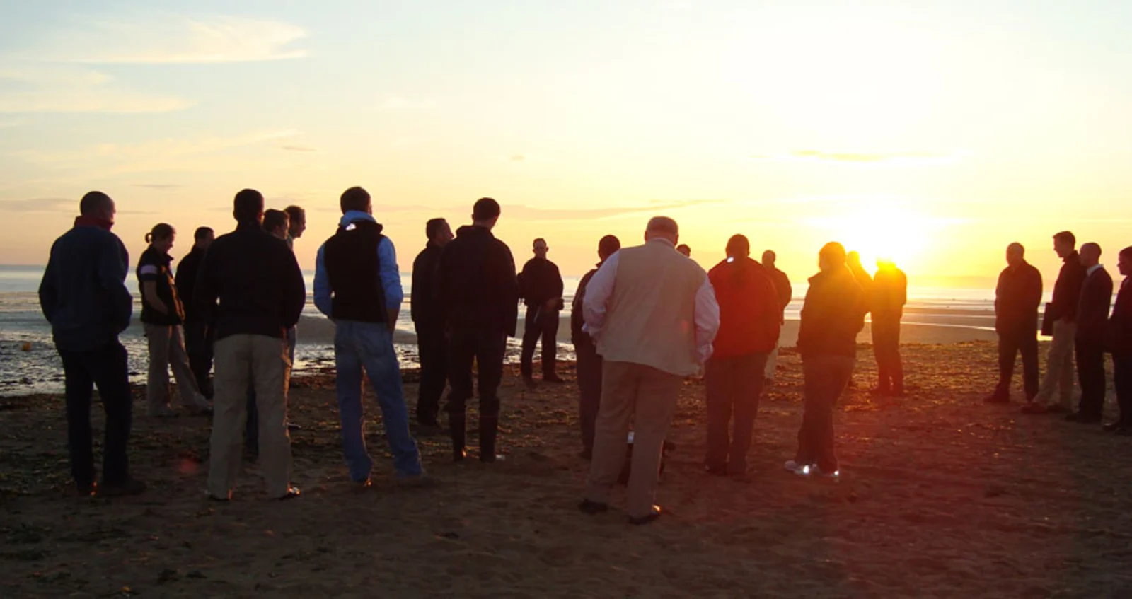 People gathered at sunset on a Normandy beach remembering D-Day.