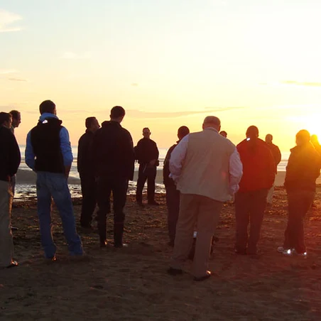People gathered at sunset on a Normandy beach remembering D-Day.