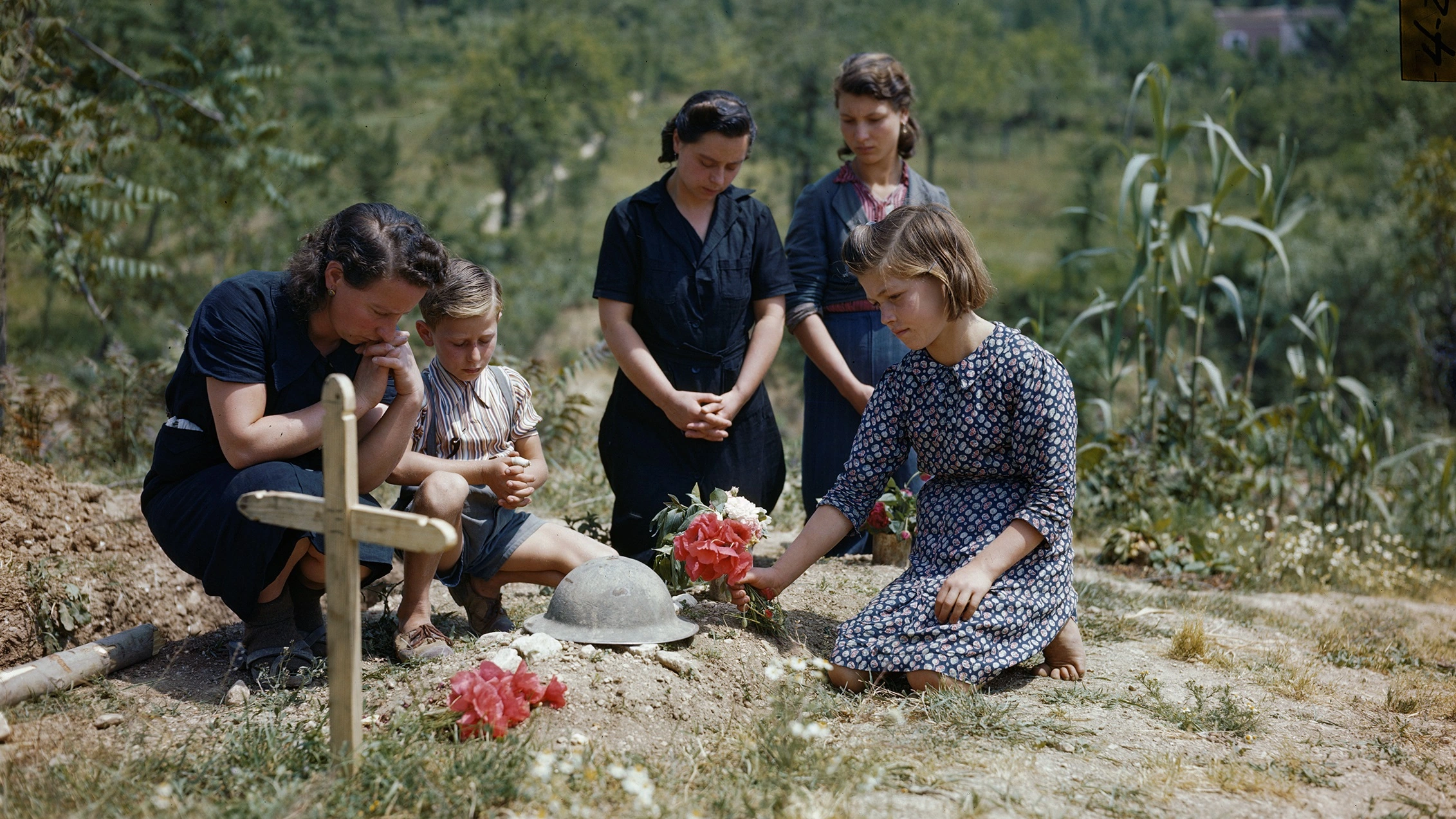 A family places flowers on the grave of an unknown British soldier killed at Cassino.  Credit: ©IWM (TR 001802) 