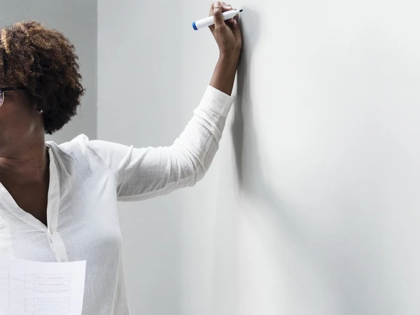 Remembrance Travel support for teachers – woman standing at a white board about to write.