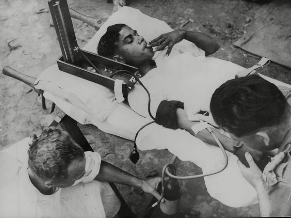Soldier on stretcher having blood taken