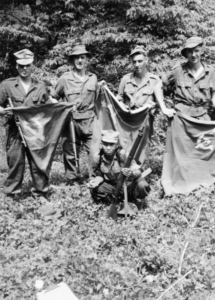 Men of a contact section of a patrol from the Cameronians (Scottish Rifles) displaying flags and caps taken from communist guerrillas 