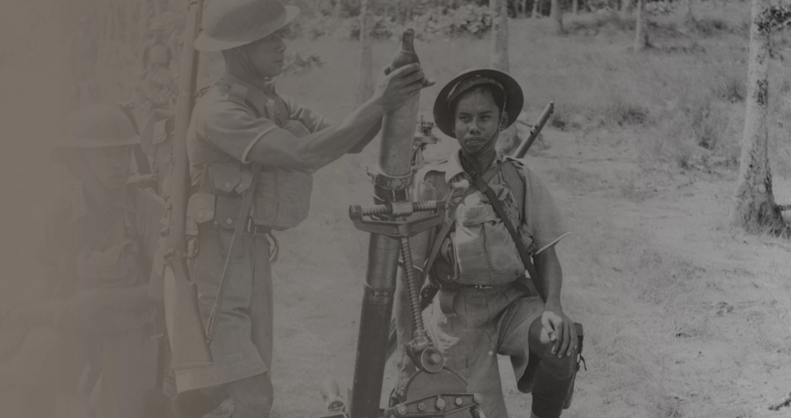 A group of Malaysian soldiers, under the command of the British, prepare to fire a mortar during a battle on the Malay Peninsula