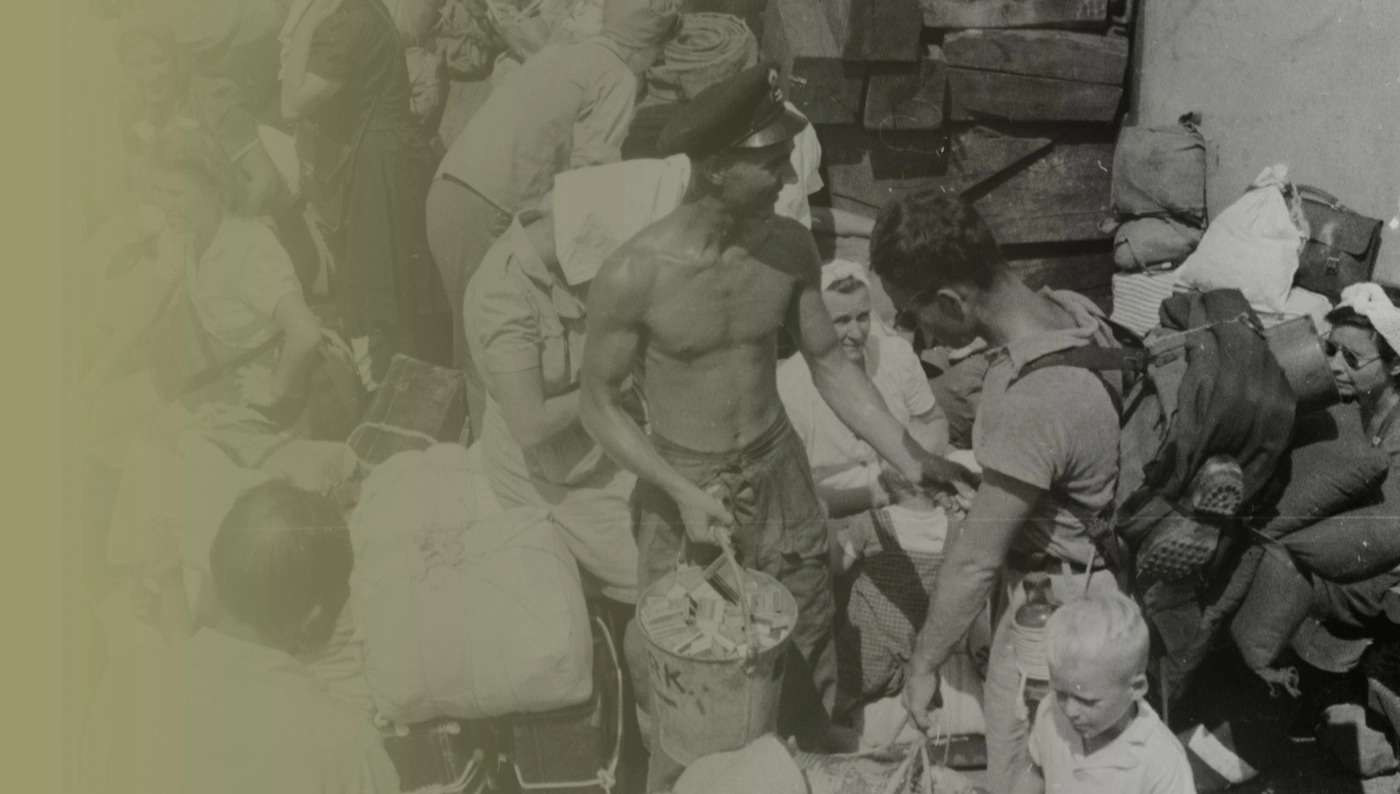 VJ DAY-THEMEHERO-5-ASSET-012 Petty Officer A E Eastlake, of Bethnal Green handing out cigarettes on board a landing craft