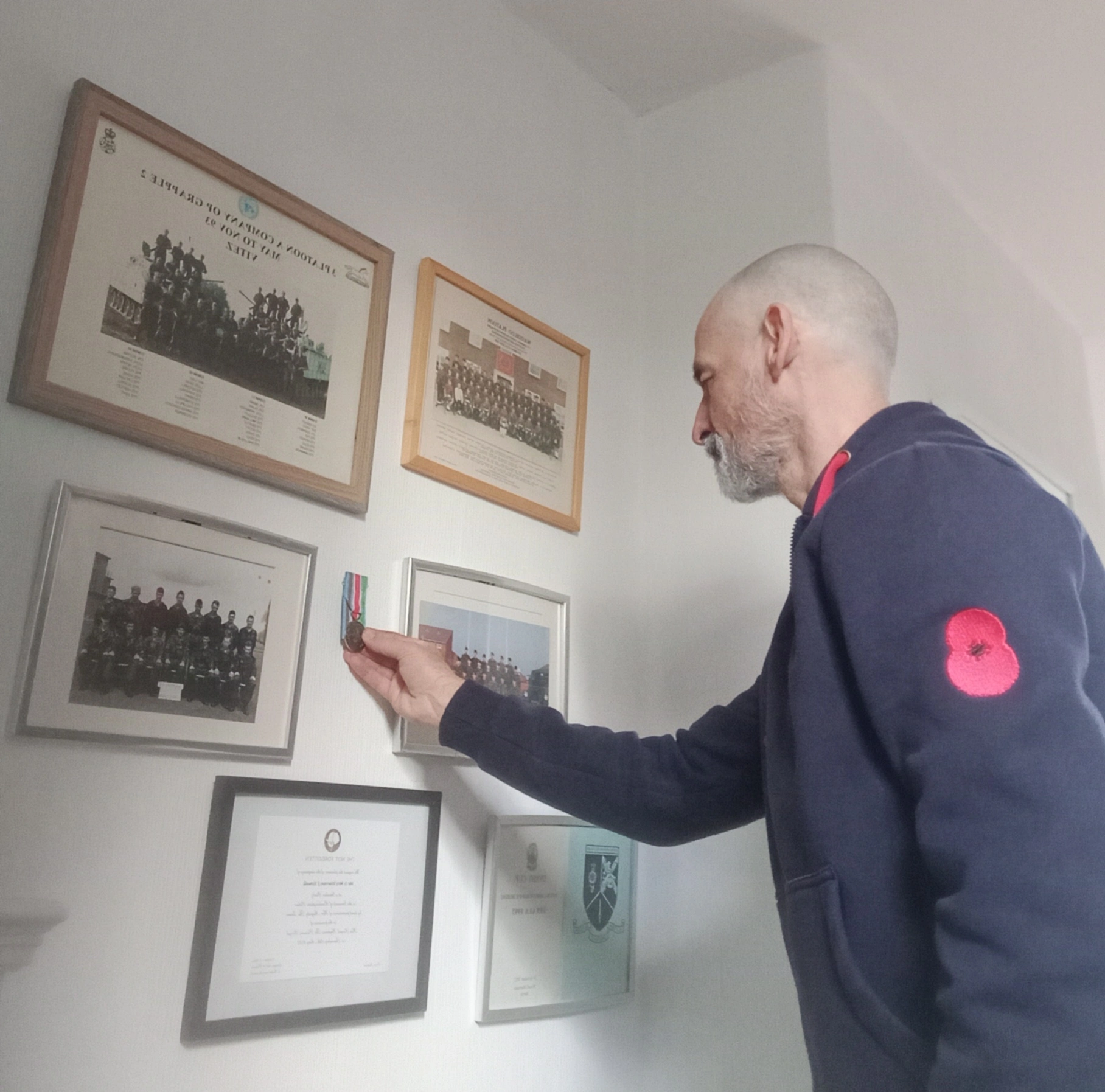 Warren Howell putting medals on wall