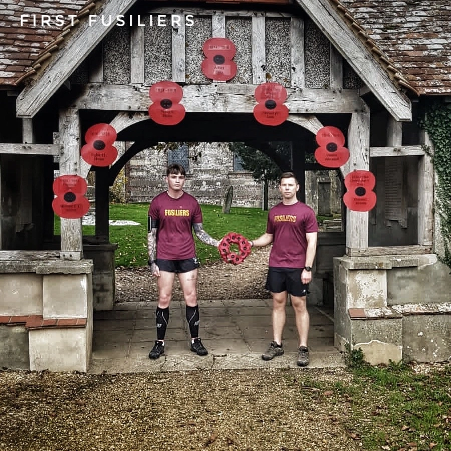 two fusiliers at a poppy wreath handover