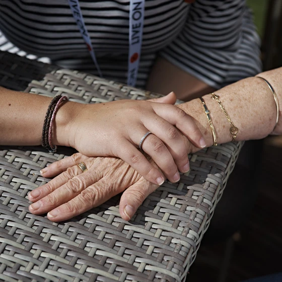 An Admiral Nurse holding the hand of an elderly female veteran