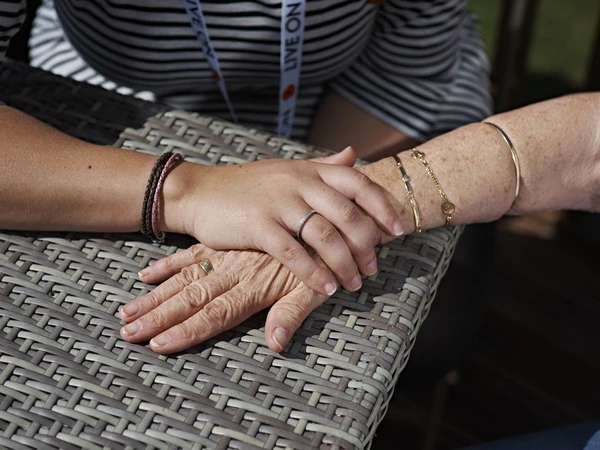 An Admiral Nurse holding the hand of an elderly female veteran