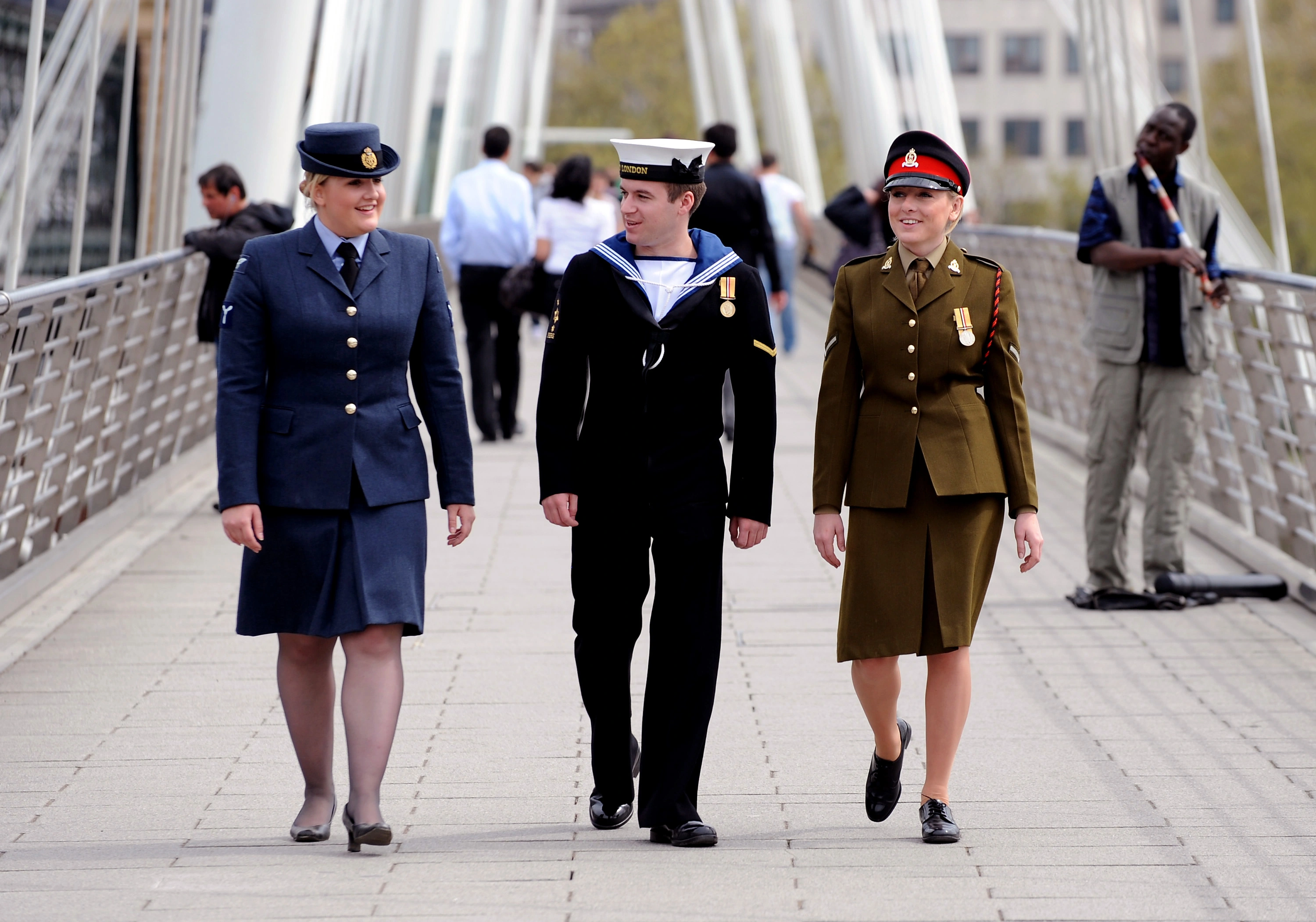 Three uniformed personnel walking across a bridge