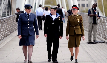Three uniformed personnel walking across a bridge