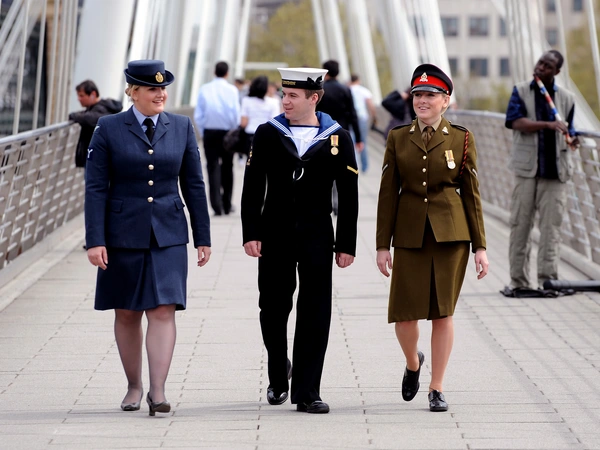 Three uniformed personnel walking across a bridge
