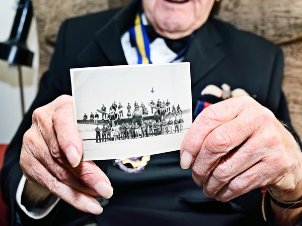 Bill Harrison holds photo of 603 Squadron crew from 1944