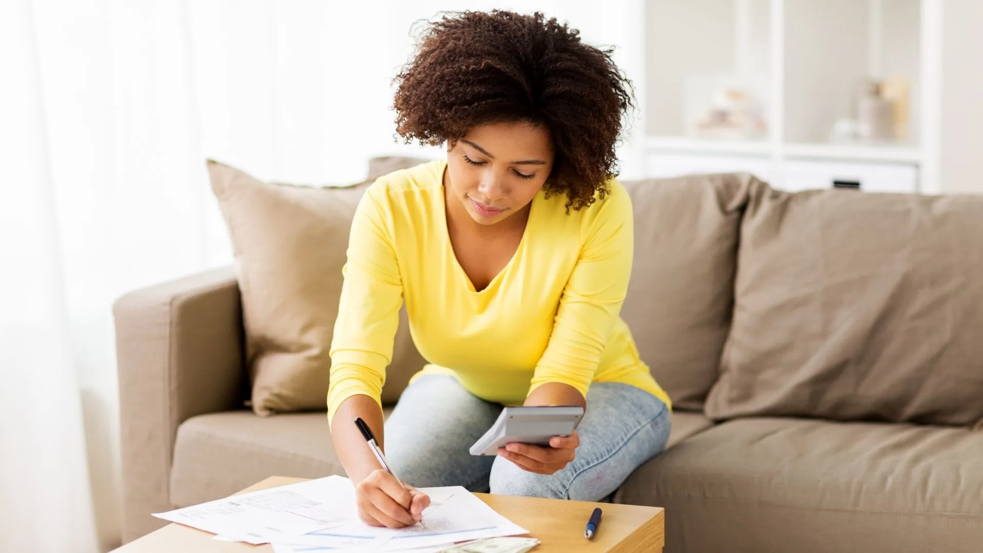 A woman sat on a sofa checking her finances