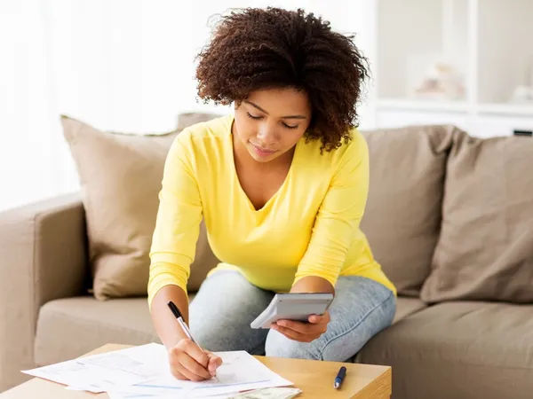 A woman sat on a sofa checking her finances