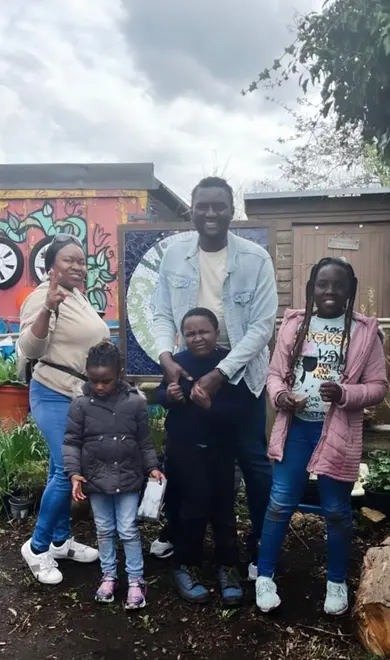 emmanuel image 2 Emmanuel is photographed with his family - his wife adn their three children. They are all smiling for the picture and standing in a relaxed manner.