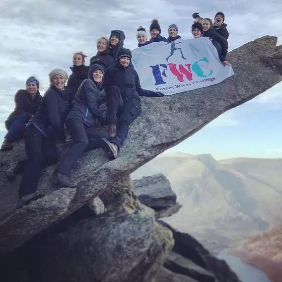 The Forces Wives on a rock with a flag