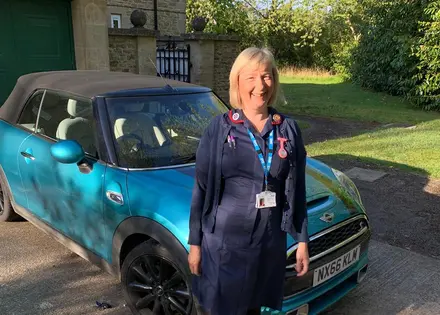 Lorraine Dooley standing in front of her blue car 