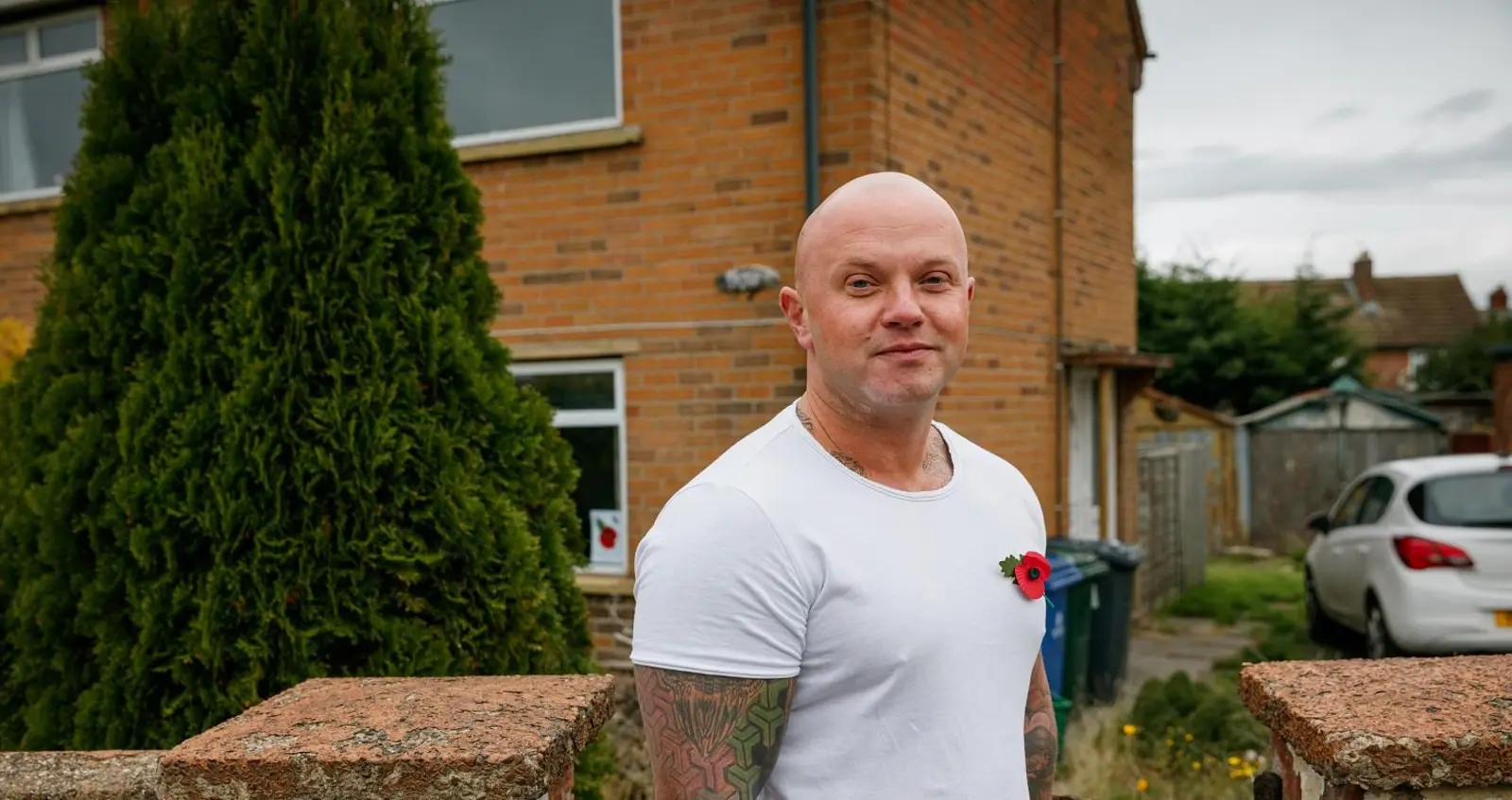 Lawrence Philips wearing a poppy outside his home