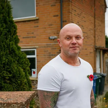 Lawrence Philips wearing a poppy outside his home