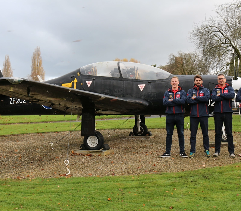 The team standing in front of a plane.